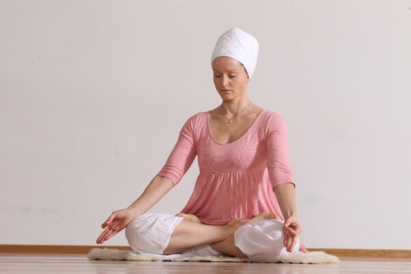 Ženska v sedeči meditaciji pri kundalini jogi z zaprtimi očmi.